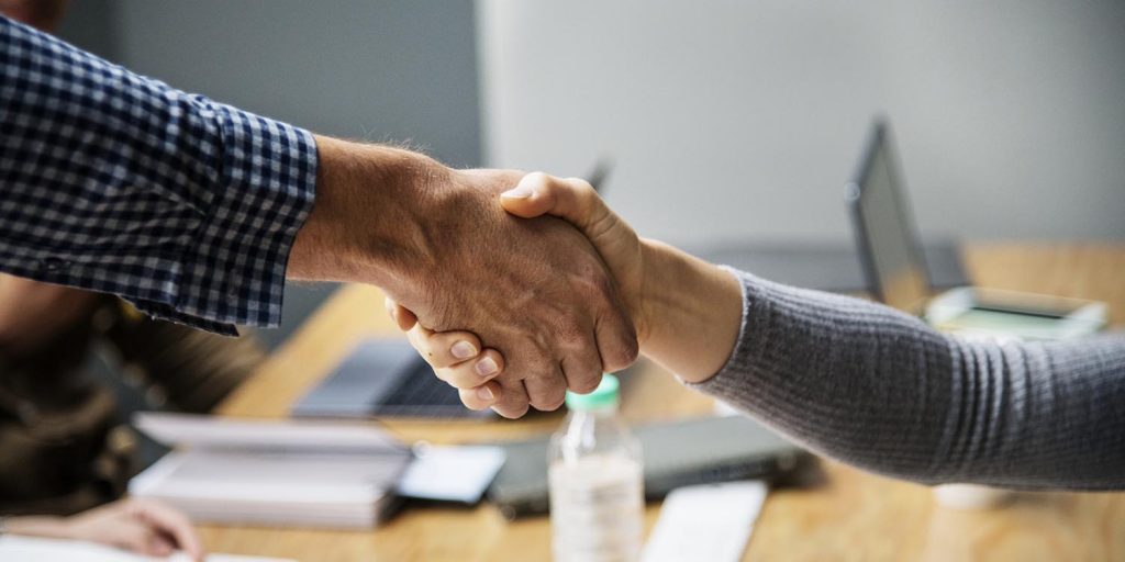 Imagem evidencia um perto de mãos simbolizando um acordo fechado.